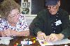 Schoolhouse Mosaic class student and program volunteer, Kathy Thompson, assists Tom Ennis with his mosaic. 